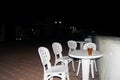 An empty white plastic summer table on the summer promenade, around a few chairs. Lunch party