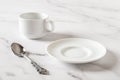 Empty white plate, cup and spoon on a marble table. Clean porcelain crockery for food design mockup. Breakfast, eat and drink, Royalty Free Stock Photo