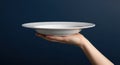 Empty white plate on hand, dark blue background Royalty Free Stock Photo