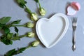 empty white plate with hearts on Ultimate Gray background with white roses and fork. The moment of a wedding anniversary