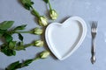 empty white plate with hearts on Ultimate Gray background with white roses and fork. The moment of a wedding anniversary