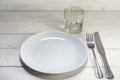 Empty white plate with knife, fork and drinking glass on a white Royalty Free Stock Photo