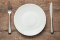 Empty white plate with knife and fork on a wooden table Royalty Free Stock Photo