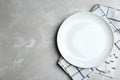 Empty white plate and napkin on grey marble table, flat lay. Space for text Royalty Free Stock Photo