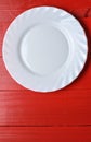 Empty white plate on red wooden background. Copy space