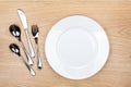 Empty white plate with silverware on wooden table Royalty Free Stock Photo