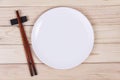 Empty white plate and sushi chopsticks on wood background Royalty Free Stock Photo