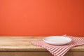 Empty white plate with tablecloth on wooden table over red wall Royalty Free Stock Photo