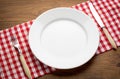 Empty white plate on wooden table over red grunge Royalty Free Stock Photo