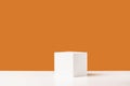 Empty white podium stage made with white cube on orange backdrop Royalty Free Stock Photo