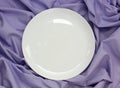 Empty white porcelain plate on a purple-striped tablecloth Royalty Free Stock Photo