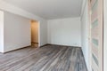 Empty white room with washed floating gray wooden laminate flooring and newly painted wall in background