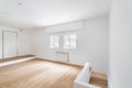 Empty white room with windows and hardwood floor after renovation. New apartment for rent or sale. Royalty Free Stock Photo