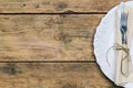 Empty white rustic plate on old wooden background with knife, fork and napkin. R Royalty Free Stock Photo