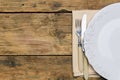 Empty white rustic plate on old wooden background with knife, fork and napkin. Rustic food concept. Royalty Free Stock Photo