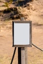 Empty white sign with partly broken wooden frame on a sandy beach Royalty Free Stock Photo
