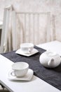 Empty white tea set, cup, saucer and teapot on the table. Porcelain dishes, selective focus