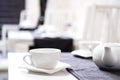 Empty white tea set, cup, saucer and teapot on the table. Porcelain dishes, selective focus