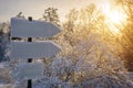 Empty white track pointers, guidepost in sunlight against winter nature background. Directional arrow signs on wooden pole in Royalty Free Stock Photo