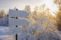 Empty white track pointers, guidepost in sunlight against winter nature background. Directional arrow signs on wooden pole in Royalty Free Stock Photo