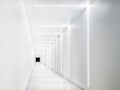 Empty white tunnel with a dark exit at the end