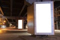 An empty white vertical light box installed under the expressway