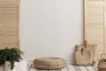 Empty white wall between wooden screen in bright interior with wicker pouf and straw bags