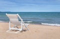 Empty white wooden beach chair on sandy tropical beach with white waves Royalty Free Stock Photo