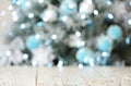 Empty white wooden table and blurred fir tree with Christmas lights on background, bokeh effect Royalty Free Stock Photo