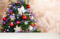 Empty white wooden table and blurred fir tree with Christmas lights on background. Space for design Royalty Free Stock Photo