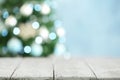 Empty white wooden table and blurred fir tree with Christmas lights on background. Space for design Royalty Free Stock Photo