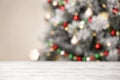 Empty white wooden table and blurred fir tree with Christmas lights on background. Space for design Royalty Free Stock Photo