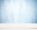 Empty white wooden table over blue cement wall. Royalty Free Stock Photo