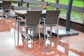 Empty wicker chairs and tables on a wet cafe patio reflecting in the brick pavement after rain Royalty Free Stock Photo