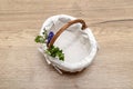 An empty wicker Easter basket, decorated with boxwood and catkins, standing on a table.