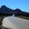 Empty winding curved road with distant mountains and blue sky