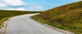 Empty winding road disappearing behind the hill Royalty Free Stock Photo