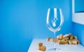 An empty wine glass on a blue background stands on a white table. Corks from wine bottles. Tasting expensive wine. Royalty Free Stock Photo