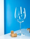 An empty wine glass on a blue background stands on a white table. Corks from wine bottles. Tasting expensive wine. Royalty Free Stock Photo