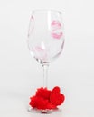 Empty wine glass with lip print and red heart decoration on white background. Vertical photo Royalty Free Stock Photo