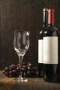 Empty wine glass next to two bottles of red wine on a rustic wooden table and dark background Royalty Free Stock Photo