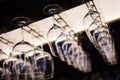 Empty wine glasses hanging upsidedown in bar interior.