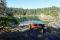 An empty wood bench overlooking a beautiful serene cove surrounded by rocky shore and forests Royalty Free Stock Photo