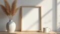 Empty wood frame mockup on shelf with pampas grass decor and white mug. Clean background with natural light, shadow patterns. Royalty Free Stock Photo