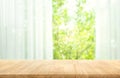 Empty of wood table top on blur of curtain with window view green from tree garden background Royalty Free Stock Photo