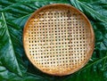 Empty wooden bamboo threshing basket on Noni or Morinda Citrifolia leaves background Royalty Free Stock Photo