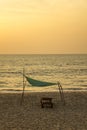 Empty wooden beach bed on the yellow sand under a green canopy against the ocean and the evening sunset sky Royalty Free Stock Photo