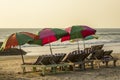 Empty wooden beach loungers with striped mattresses under bright large sun umbrellas on the sand against the background of the Royalty Free Stock Photo