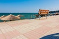 Empty wooden bench at promenade above public beach next to the c Royalty Free Stock Photo