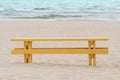 Empty wooden bench on sandy beach in front of sea Royalty Free Stock Photo